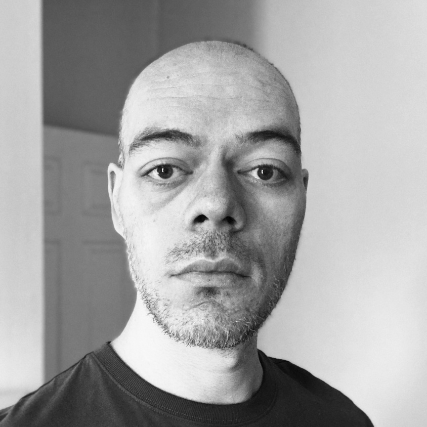 Grayscale headshot of Karl with a blank expression.